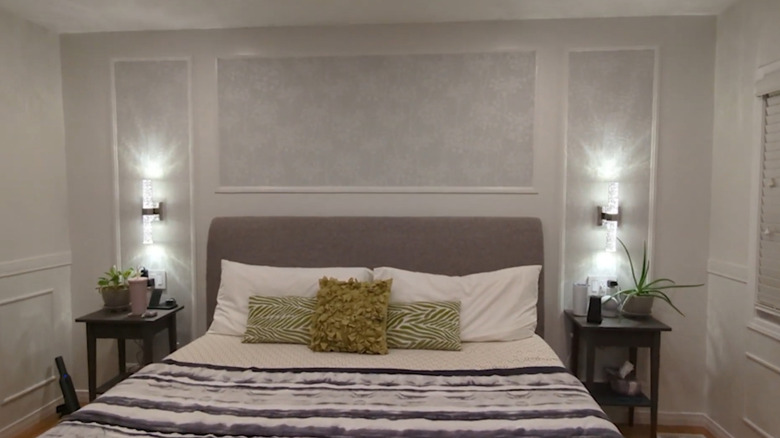 A bedroom with wallpaper panel accents on the walls.