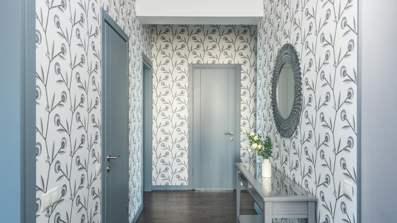 An entry hallway with a blue door and trim with wallpapered walls.