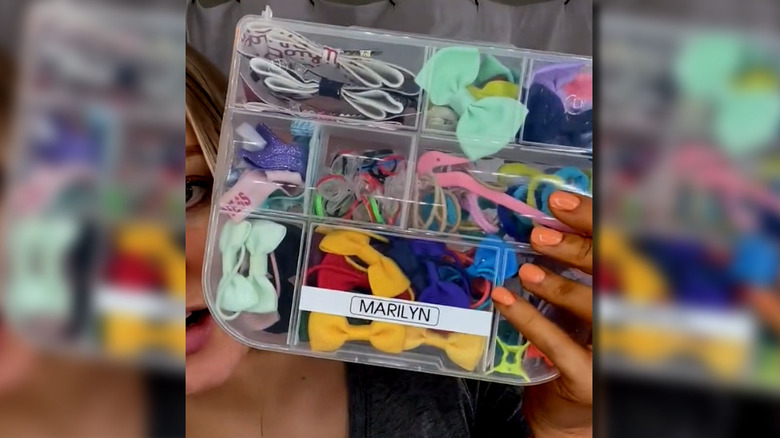 Woman holding up clear plastic case used to organize hair accessories.