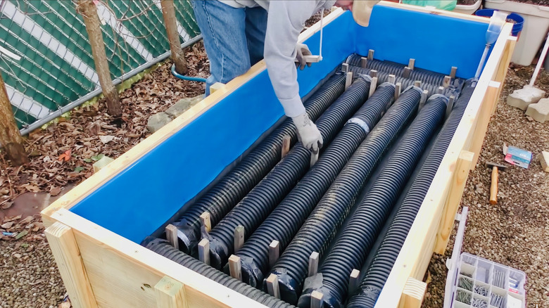 Man assembles inner workings of a raised bed with sub-irrigation self-watering system.