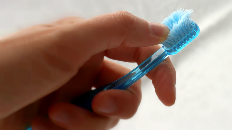Hand holding blue worn toothbrush