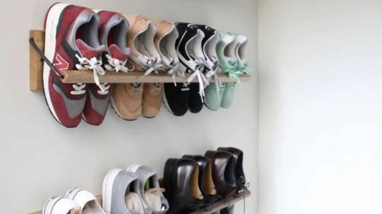Two towel rails on the wall being used to hold trainers and smart shoes.