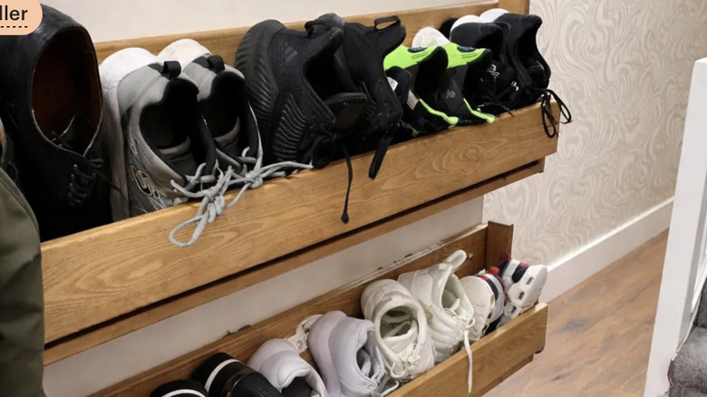 Two rows of wooden shoe racks with trainers stuffed into them