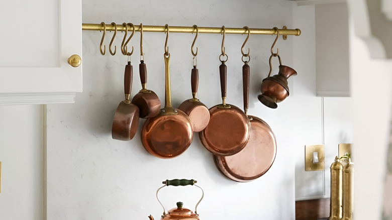 Kitchen rail rack holding pots and pans with s-hooks.