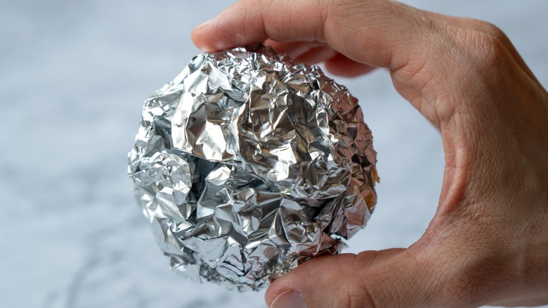 hand holding aluminum foil ball