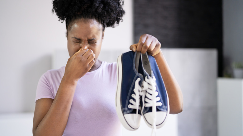 woman plugging nose near sneakers