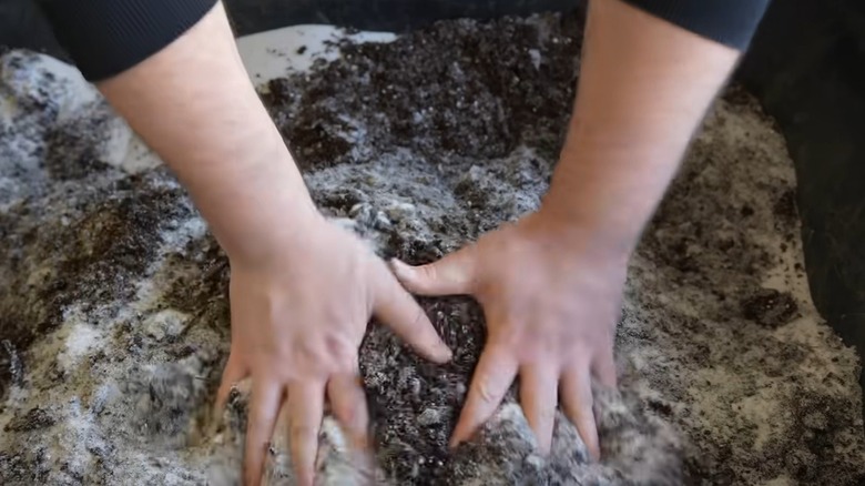 Person mixing topsoil and sand in a wheelbarrow