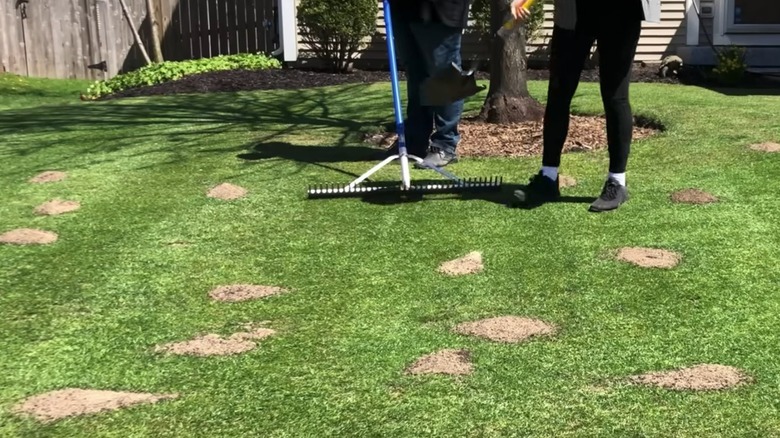 People raking sand on an uneven lawn