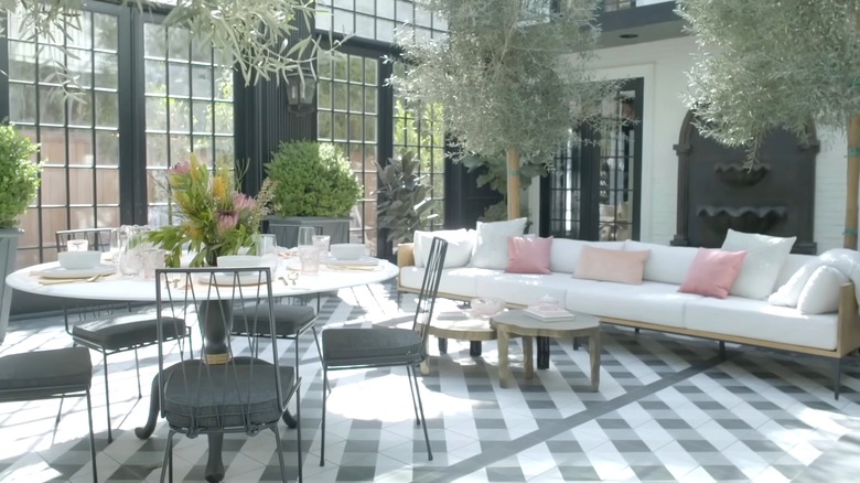 A large furnished sunroom with olive trees.
