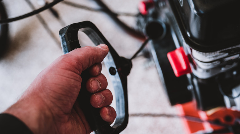 Person pulling a start cord on a snow blower