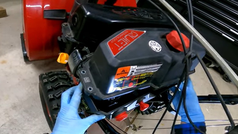Person working on a snow blower engine
