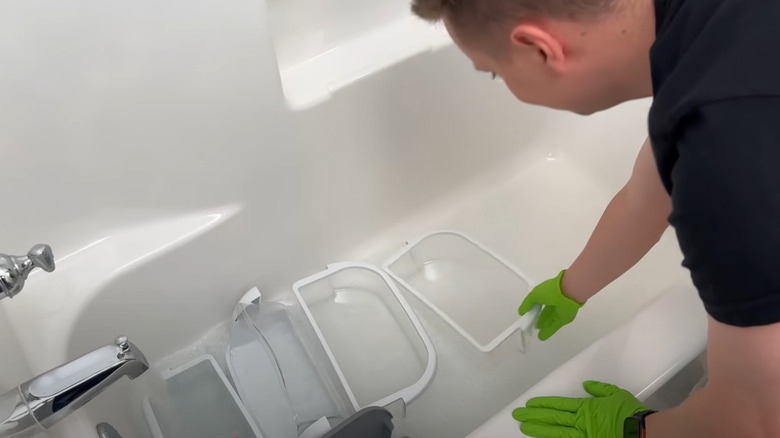 Person putting glass refrigerator shelves in the bathtub