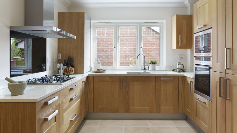 a beautiful kitchen in a modern apartment with oak fitted cupboards and drawers and cream colored granite work top.