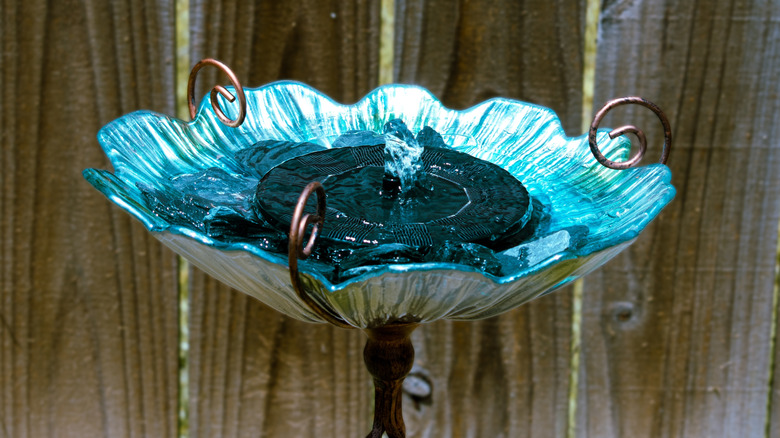 A beautiful blue birdbath with a solar fountain in the basin