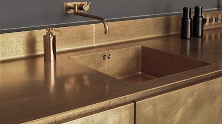 A brass countertop with brass cabinets and a gray wall color