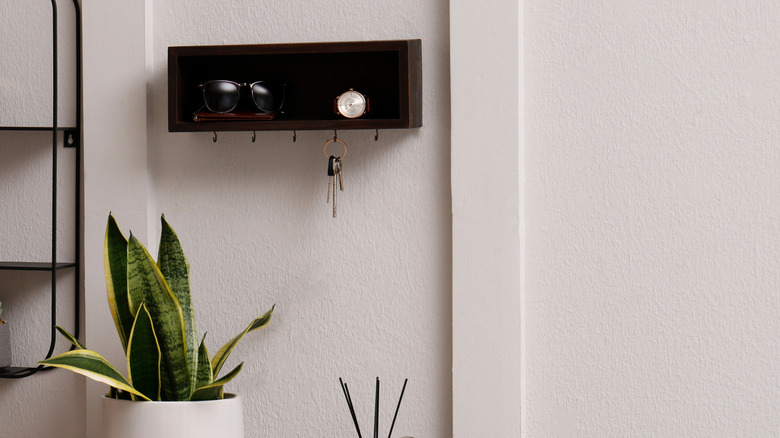 A floating shelf in an entryway with hooks underneath