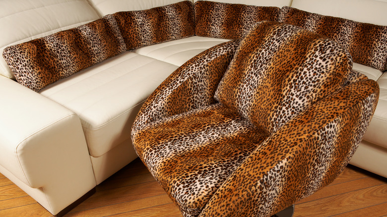 A white leather couch with animal print cushions and an animal print chair in front of it