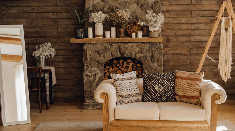 A cottagecore style living room with wooden walls and a stone fireplace