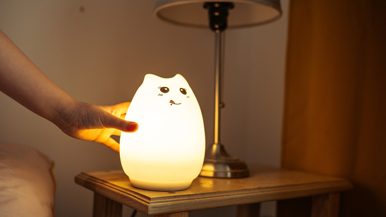 A battery-powered cat-themed night lamp on a bedside table