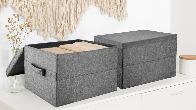 Collapsible fabric storage boxes filled with clothes sitting on top of a dresser