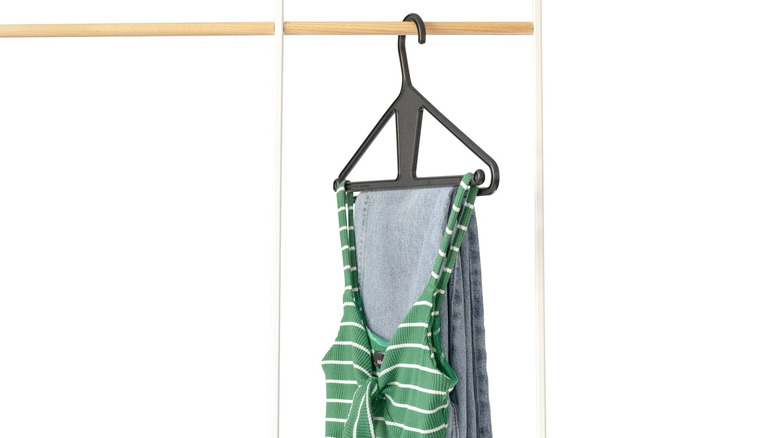 Kangaroo hanger on a wooden rod with a pair of jeans and a green and white striped tank top on it
