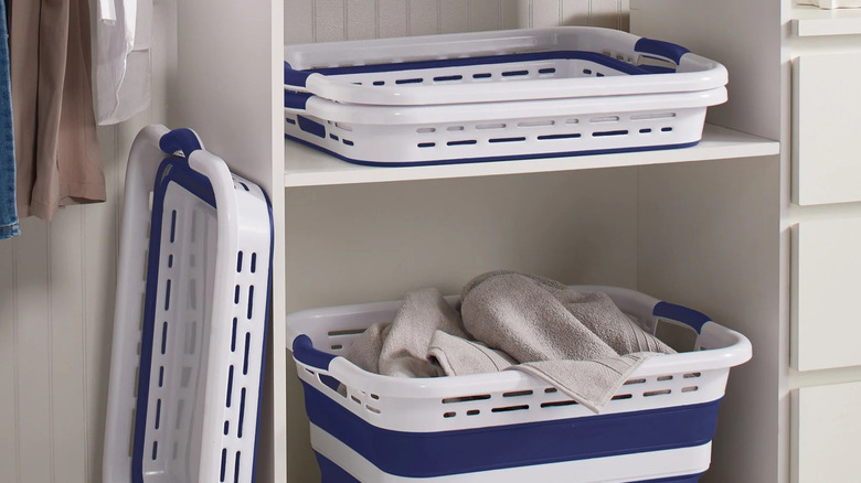 Two Pop 'N Load laundry baskets collapsed and one filled with towels on a shelf