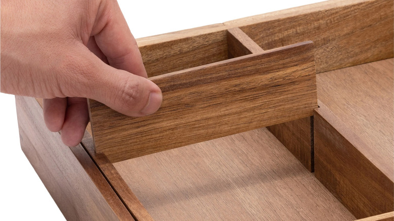 Person adjusting dividers in a wood organizer