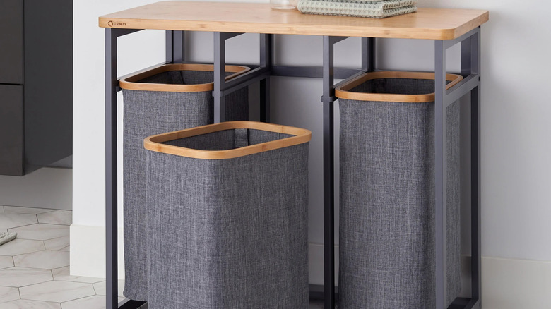 Trinity laundry station with three bins and a wood top with a towel on it