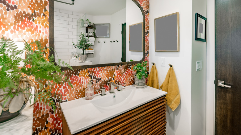 Eclectic secondary bathroom vanity with colorful wallpaper, greenery, and decor