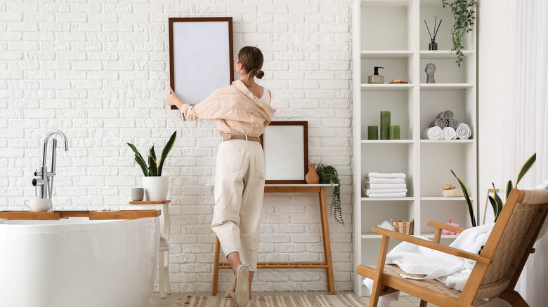 Woman hanging up decor in a stylish bathroom