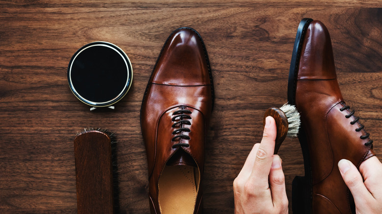 Hands shining shoes with shoe polish and a brush