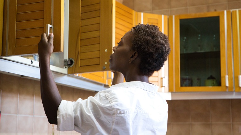 A person opening wooden kitchen cabinet doors