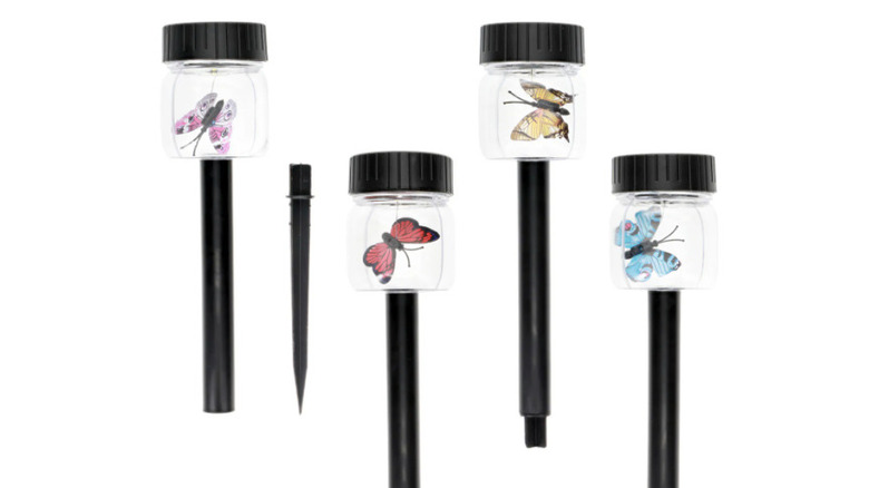 Four black solar stakes with butterflies against a white background