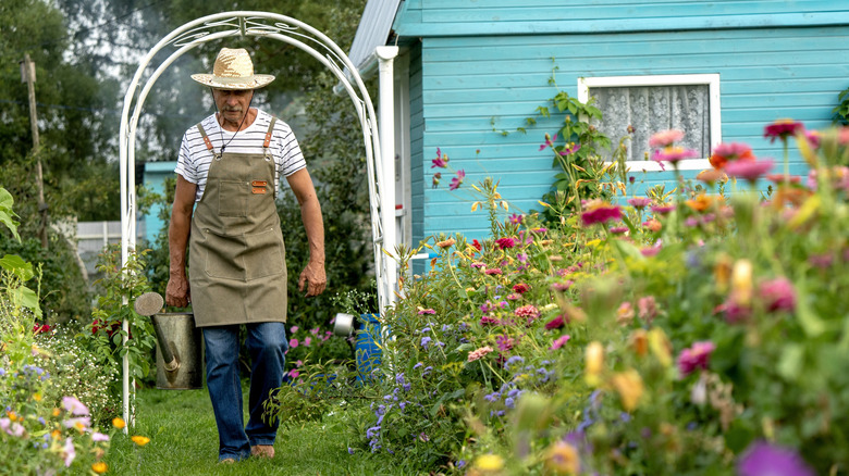 Gardener with watering can in colorful butterfly garden