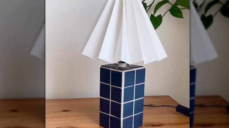A square tile base for a lamp with a white shade