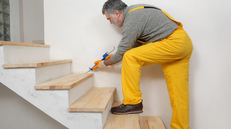 person caulking wooden staircase