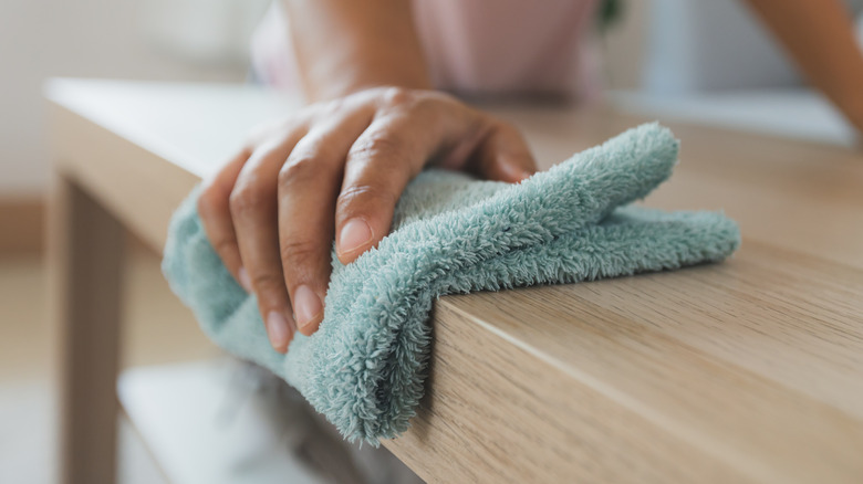 Person cleaning table with cloth