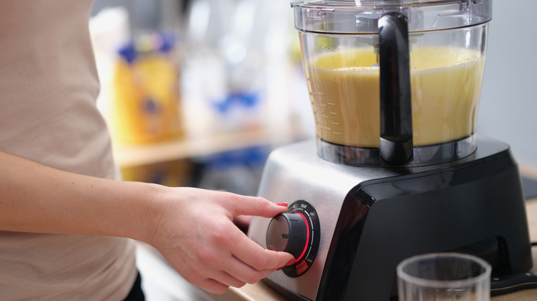 person using food processor to blend eggs