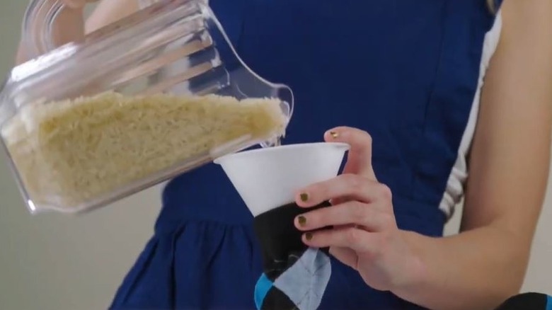 Woman pouring rice into sock for DIY heating pad