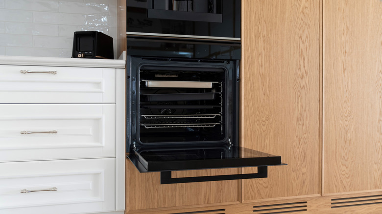 built in oven with an open door in kitchen with wood cabinets