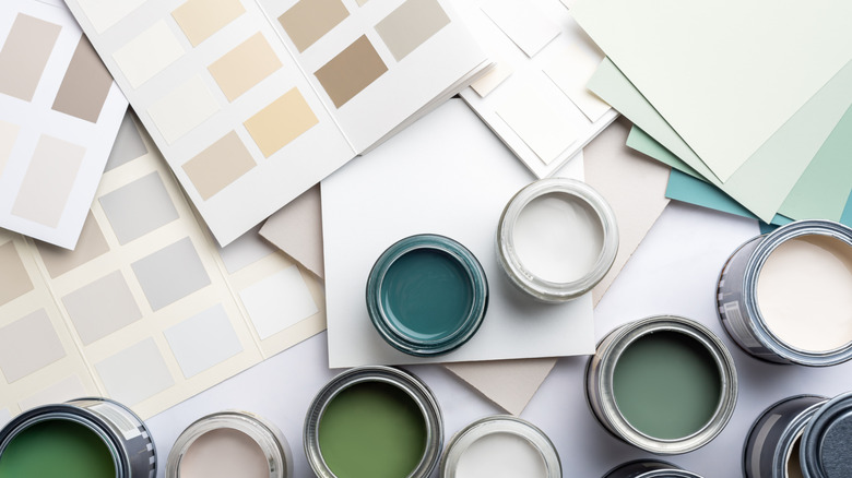 Small sample paint cans and paint swatches in neutral tones on a white surface