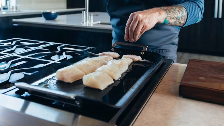 the new carbon steel Yeti griddle with fish cooking on a stove top