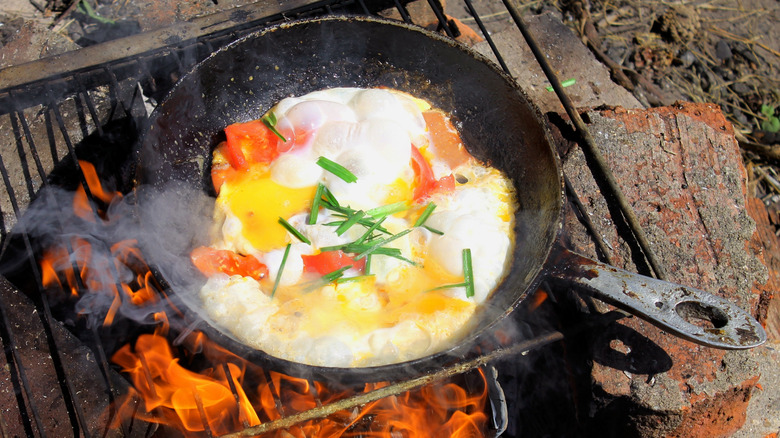 cooking on a cast iron pan over a campfire