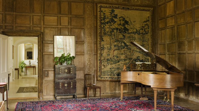 Sophisticated, traditional living room with a large antique tapestry hung on a wooden wall, paired with vintage furniture