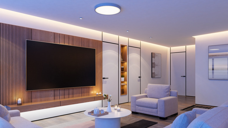 Sleek living room interior with soft lighting, comfy furniture, and a large TV screen mounted on the wall
