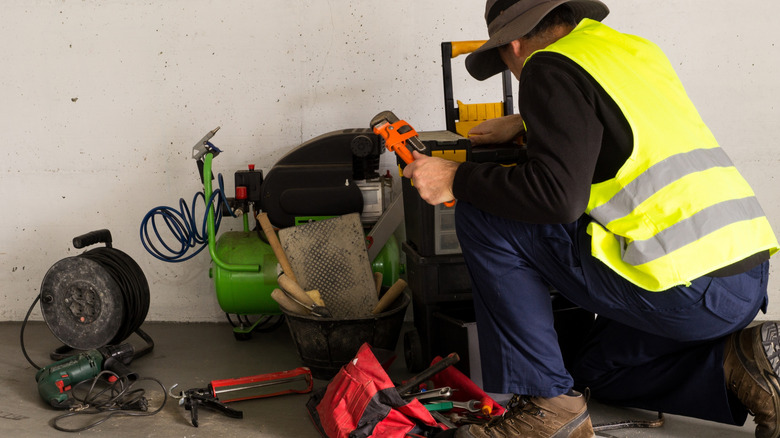 Man organizing tools into a toolbox beside some tools and a tool bag