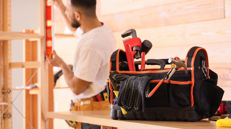 Tool bag in foreground with repairman at work in background