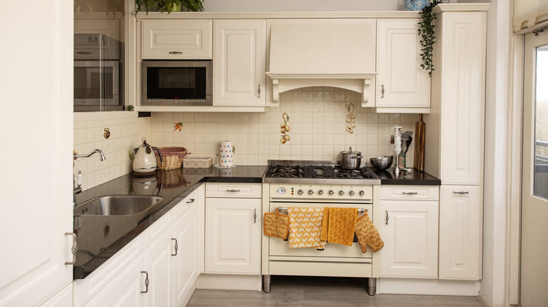 A kitchen with cream colored cabinets and tile backsplash