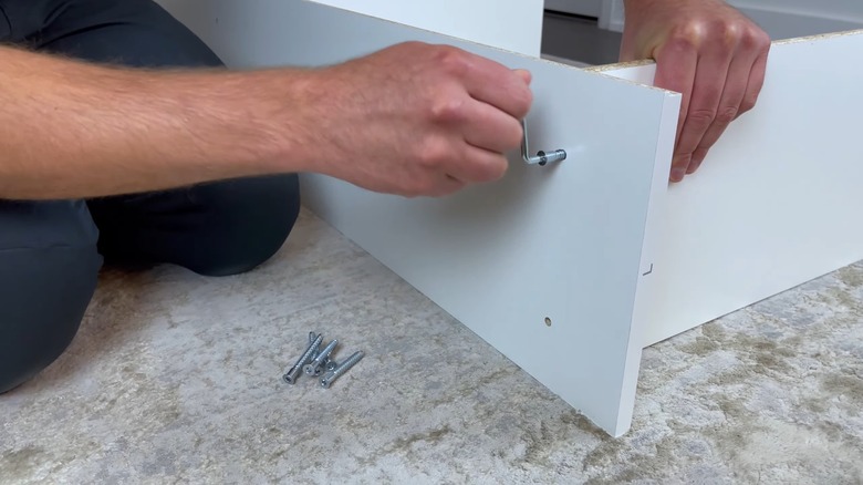 Man screwing together IKEA GERSBY bookshelf