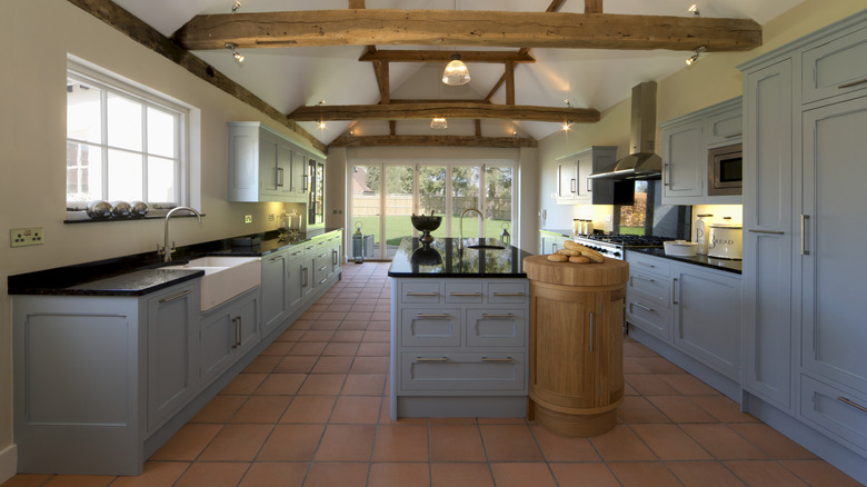 Stylish, bright kitchen with gray-blue cabinets and terracotta flooring tiles